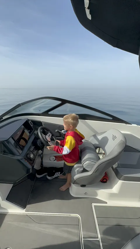 Un niño con chaleco salvavidas al timón del barco